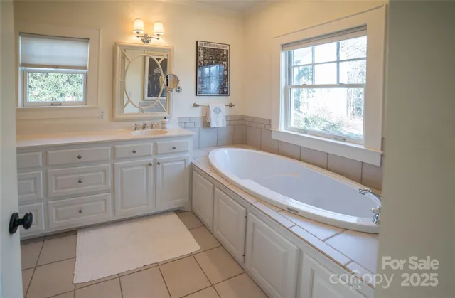 a spacious bathroom with a tub sink and mirror