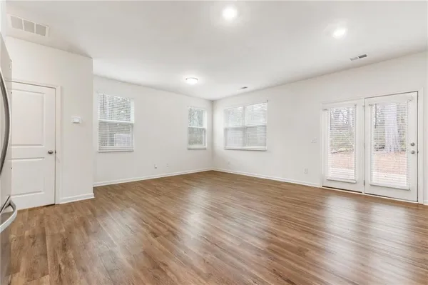 an empty room with wooden floor and windows