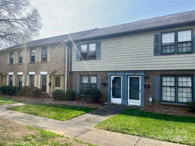 a view of a brick house with yard and plants