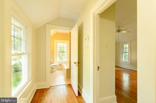 a view of a hallway with wooden floor and a bathroom