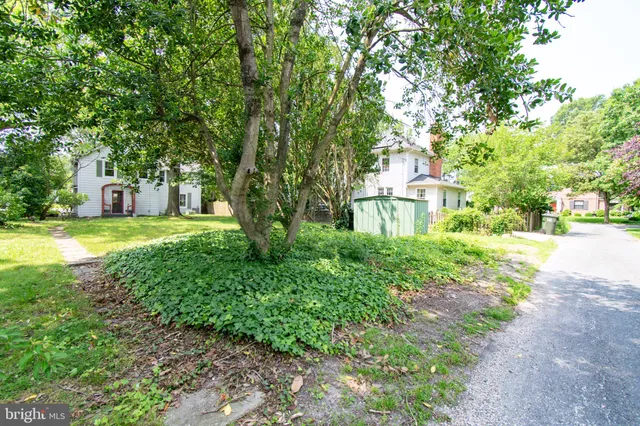 a view of a house with a big yard and large trees