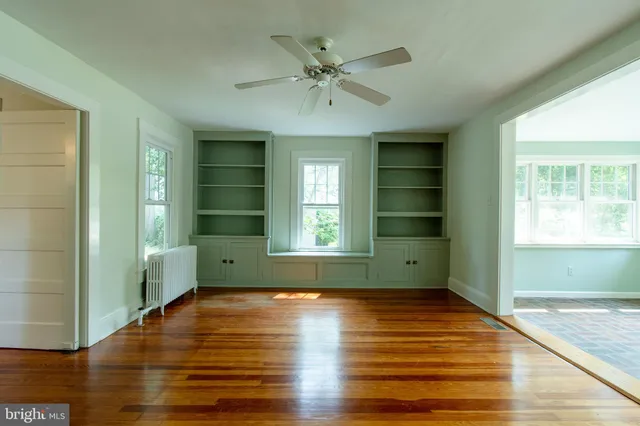 a view of empty room with wooden floor and fan