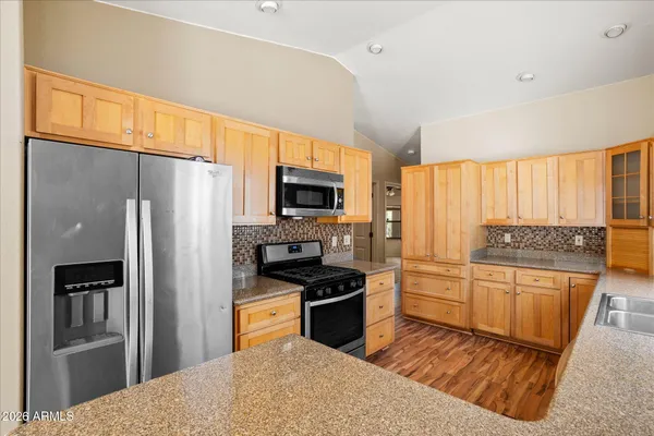 a kitchen with granite countertop a refrigerator stove top oven and sink