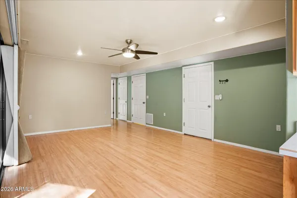 a view of an empty room with wooden floor and a ceiling fan
