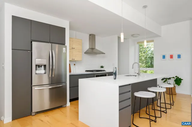 a kitchen with stainless steel appliances a refrigerator a stove a sink and white cabinets with wooden floor