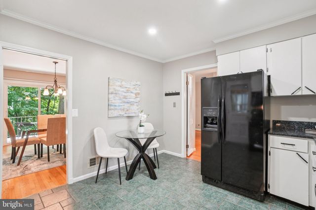 a kitchen with stainless steel appliances kitchen island granite countertop a refrigerator and a dining table