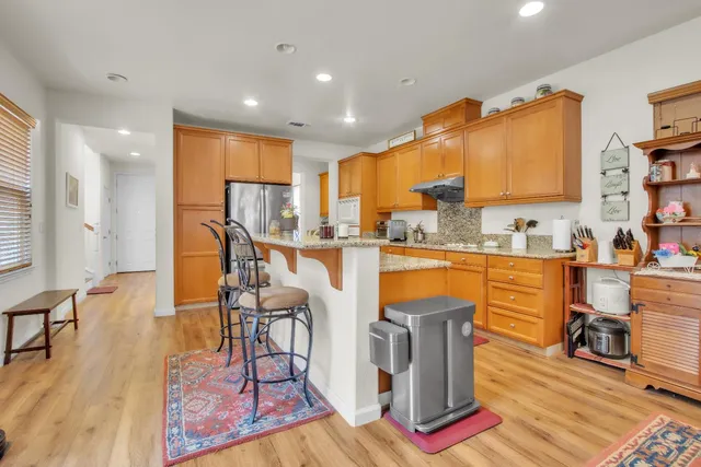 a kitchen with stainless steel appliances granite countertop a refrigerator a stove top oven and a dining table with wooden floor