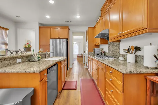 a kitchen with stainless steel appliances granite countertop sink stove refrigerator and cabinets