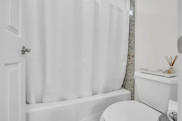 a white toilet sitting next to a shower