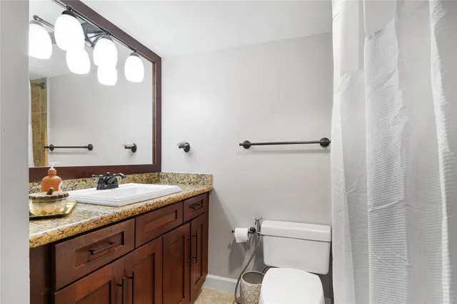 a bathroom with a granite countertop sink mirror and toilet