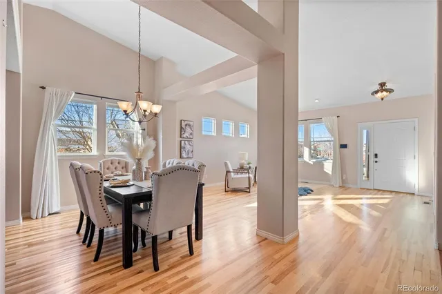 a dining room with wooden floor a chandelier a wooden table and chairs