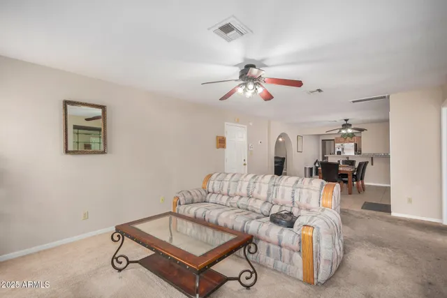 a living room with furniture kitchen view and a chandelier