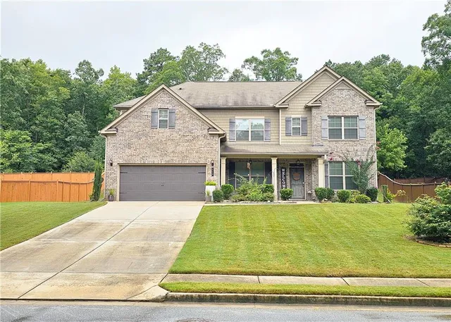 a front view of house with yard and trees in the background