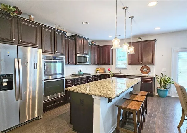 a kitchen with stainless steel appliances granite countertop a stove refrigerator sink and microwave
