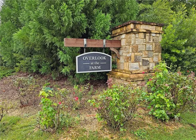 a sign board with a small yard and trees in the background