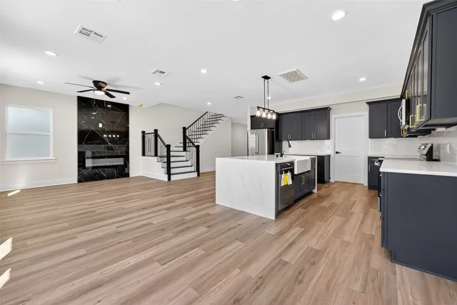 a large kitchen with stainless steel appliances kitchen island a large counter top and a stove top oven