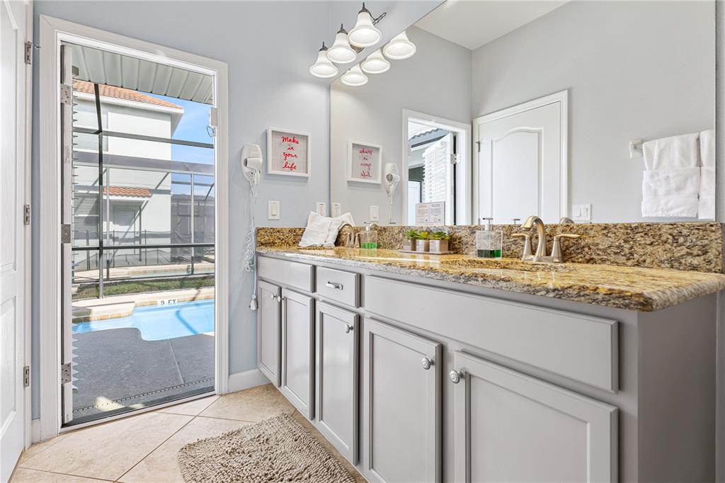 9006 Majesty Palm Road Kissimmee, FL 34747 - Photo 27 of 56 a bathroom with a granite countertop sink a mirror and a shower