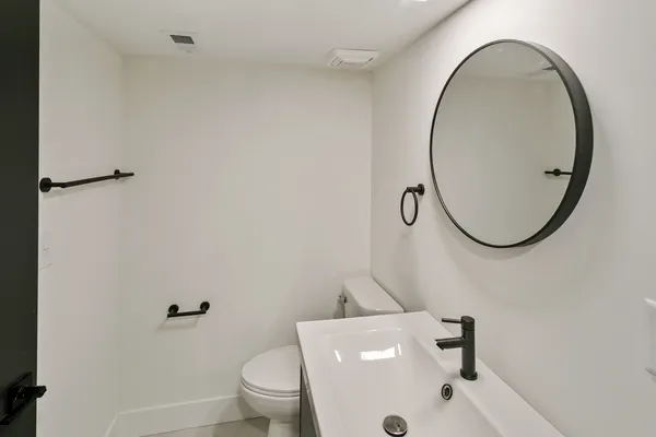 a bathroom with a sink a toilet and a mirror