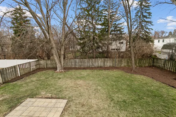 a view of backyard with wooden fence and large trees