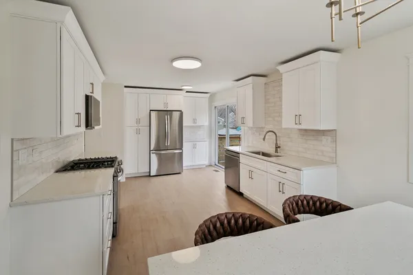 a large white kitchen with stainless steel appliances kitchen island granite countertop a refrigerator and a stove top oven