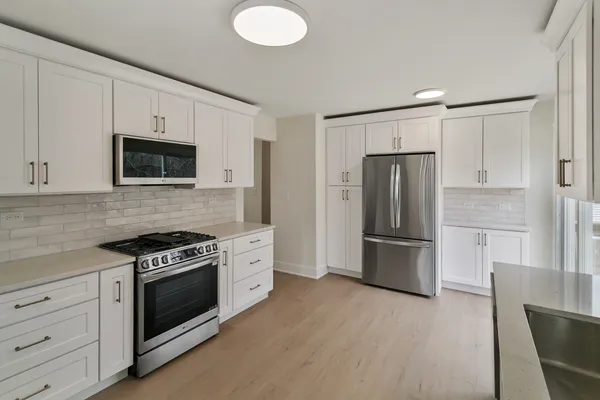 a kitchen with a stove a refrigerator and a microwave oven