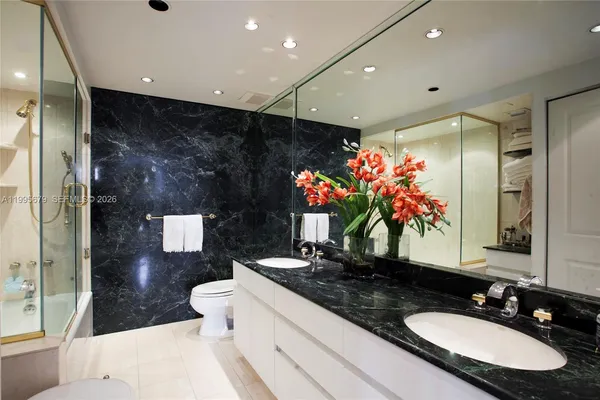 a bathroom with a granite countertop sink a toilet a mirror and shower