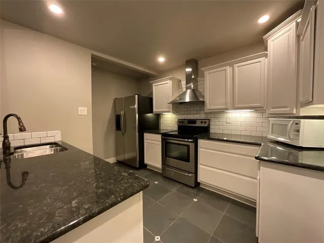 a kitchen with granite countertop a sink stainless steel appliances and cabinets