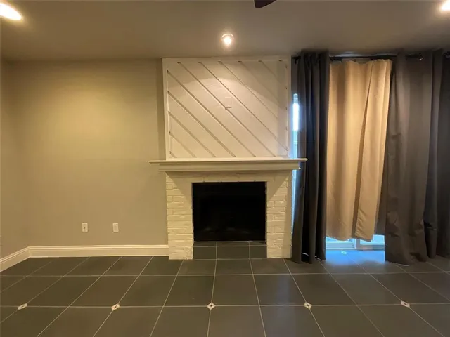 a view of an empty room with wooden floor and a fireplace