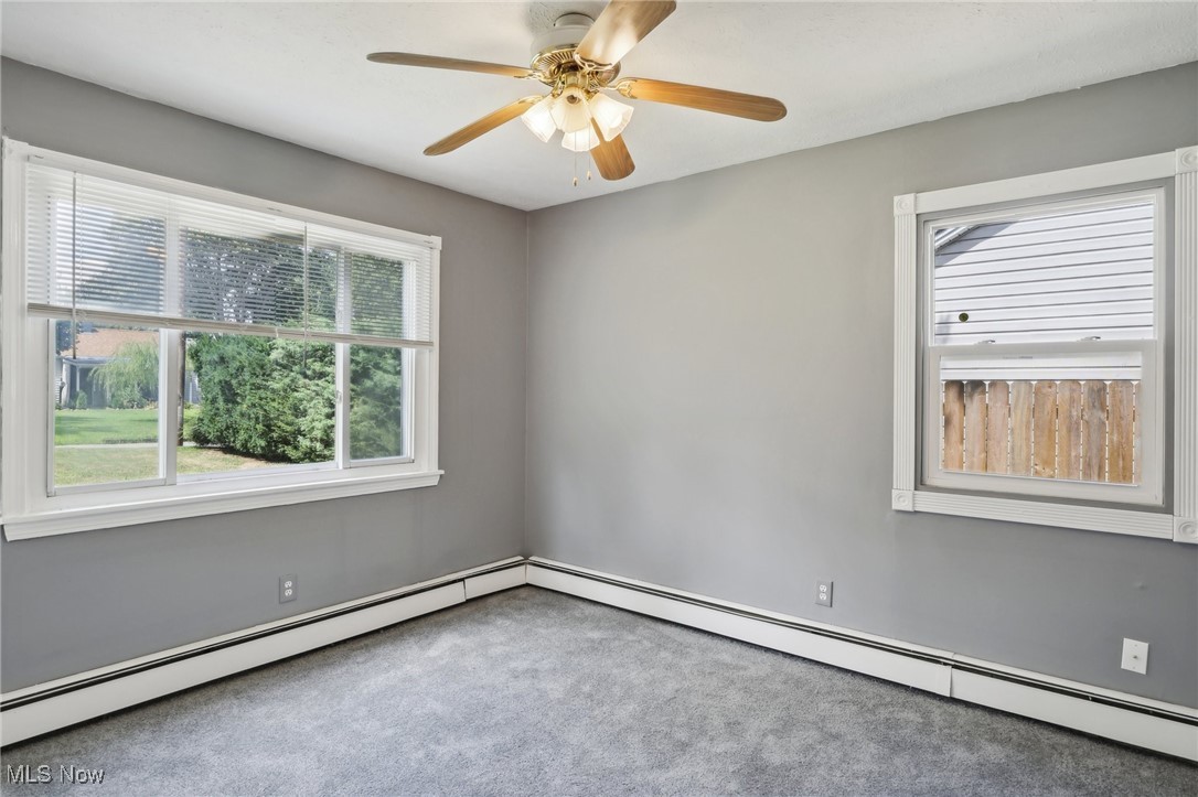 1829 Clyde Road Madison, OH 44057 - Photo 24 of 40 Carpeted empty room featuring ceiling fan, baseboard heating, and a healthy amount of sunlight