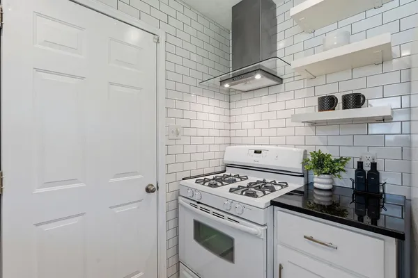 a kitchen with a stove and white cabinets