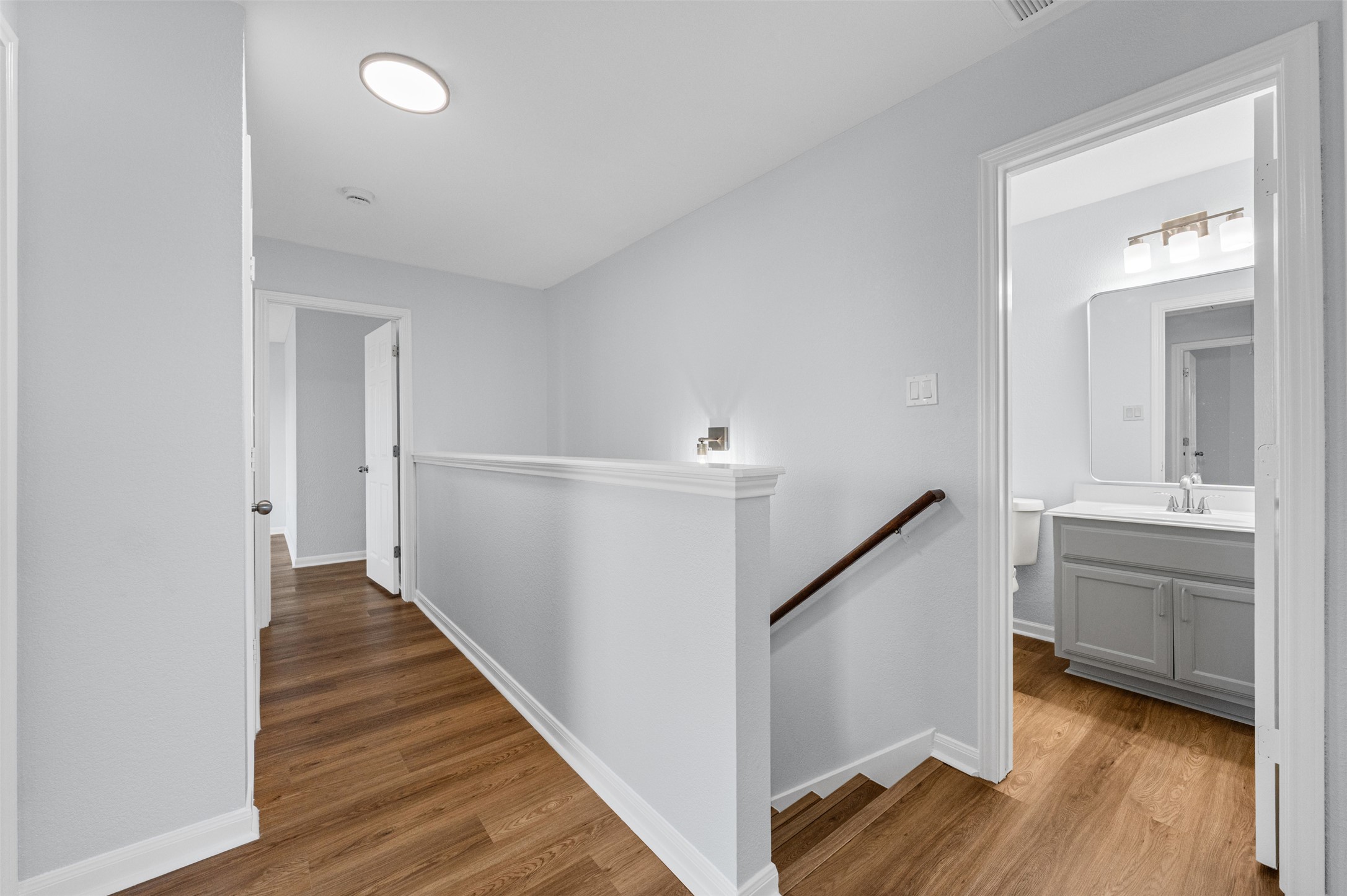 243 Engineers Pass Jarrell, TX 76537 - Photo 31 of 40 Hallway featuring wood-finish flooring, white baseboards, a contemporary ceiling light, and a dedicated wall sconce