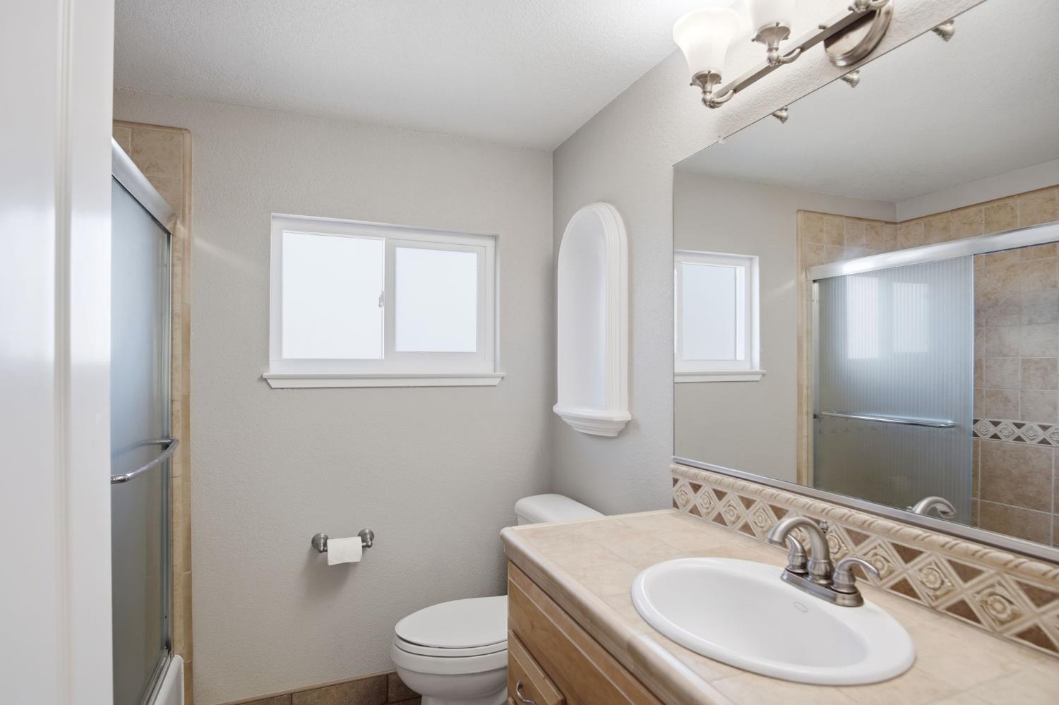16166 Lawrence Road Escalon, CA 95320 - Photo 27 of 56 a bathroom with a granite countertop sink toilet and mirror