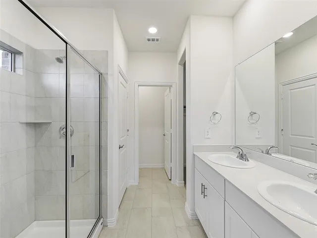 a spacious bathroom with a double vanity sink mirror and shower