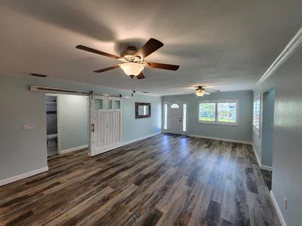 a view of an empty room with window and wooden floor