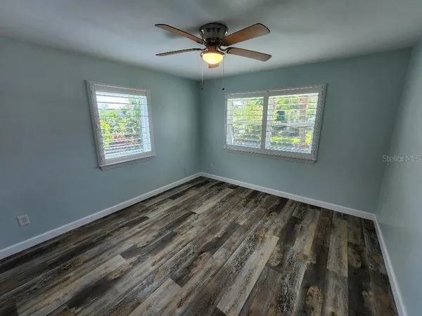 a view of an empty room and window and a ceiling fan