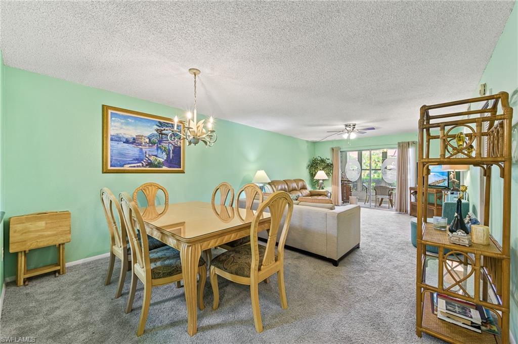 300 Valley Stream Drive, Unit A1 Naples, FL 34113 - Photo 19 of 27 a dining room with furniture a window and a chandelier