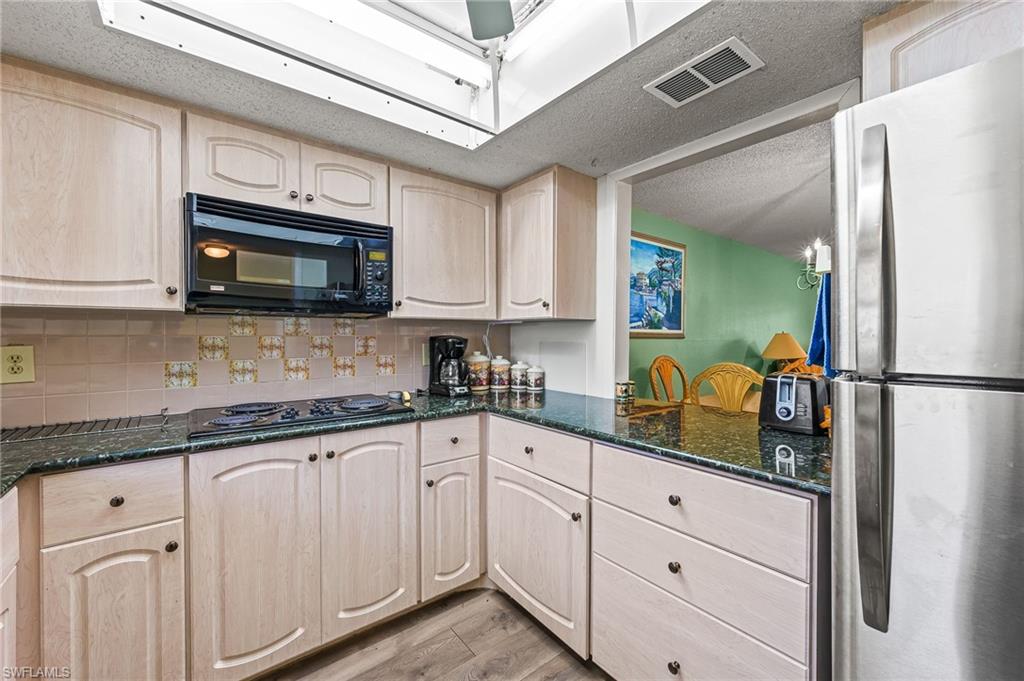 300 Valley Stream Drive, Unit A1 Naples, FL 34113 - Photo 25 of 27 a kitchen with granite countertop white cabinets and stainless steel appliances