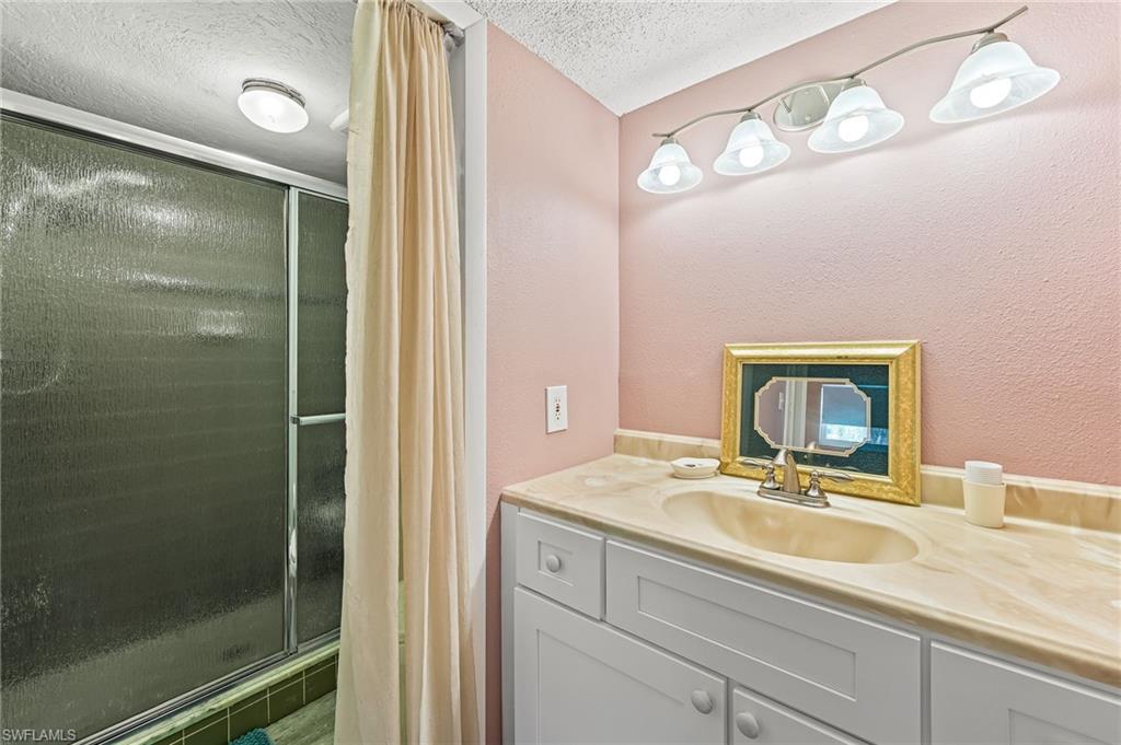 300 Valley Stream Drive, Unit A1 Naples, FL 34113 - Photo 5 of 27 a bathroom with a sink a mirror and a shower