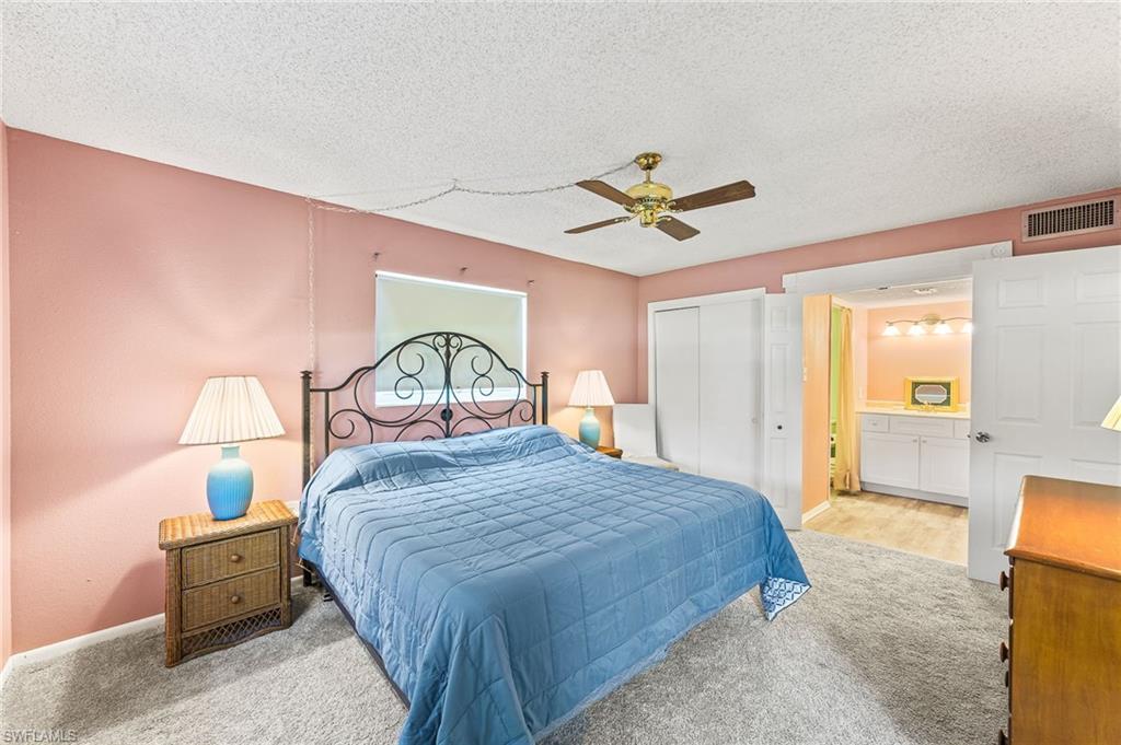 300 Valley Stream Drive, Unit A1 Naples, FL 34113 - Photo 10 of 27 a bedroom with a bed a chandelier and a dresser