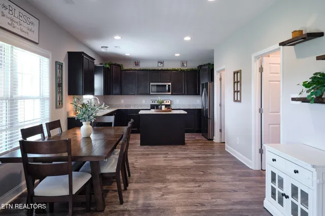 a kitchen with granite countertop a refrigerator a stove a sink dishwasher and white cabinets with wooden floor