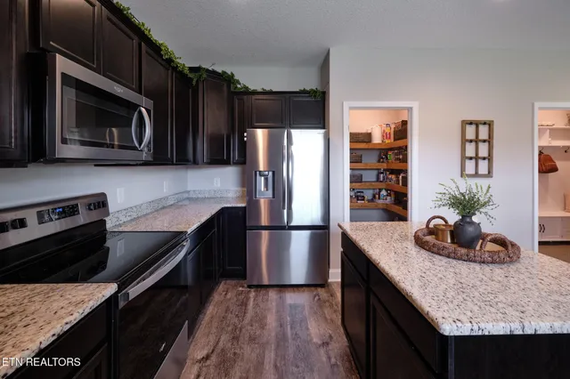 a kitchen with granite countertop a stove microwave and refrigerator