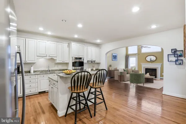 a kitchen with stainless steel appliances granite countertop a stove top oven a refrigerator a sink and a dining table with wooden floor