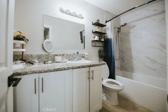 a bathroom with a granite countertop sink toilet mirror vanity and bathtub