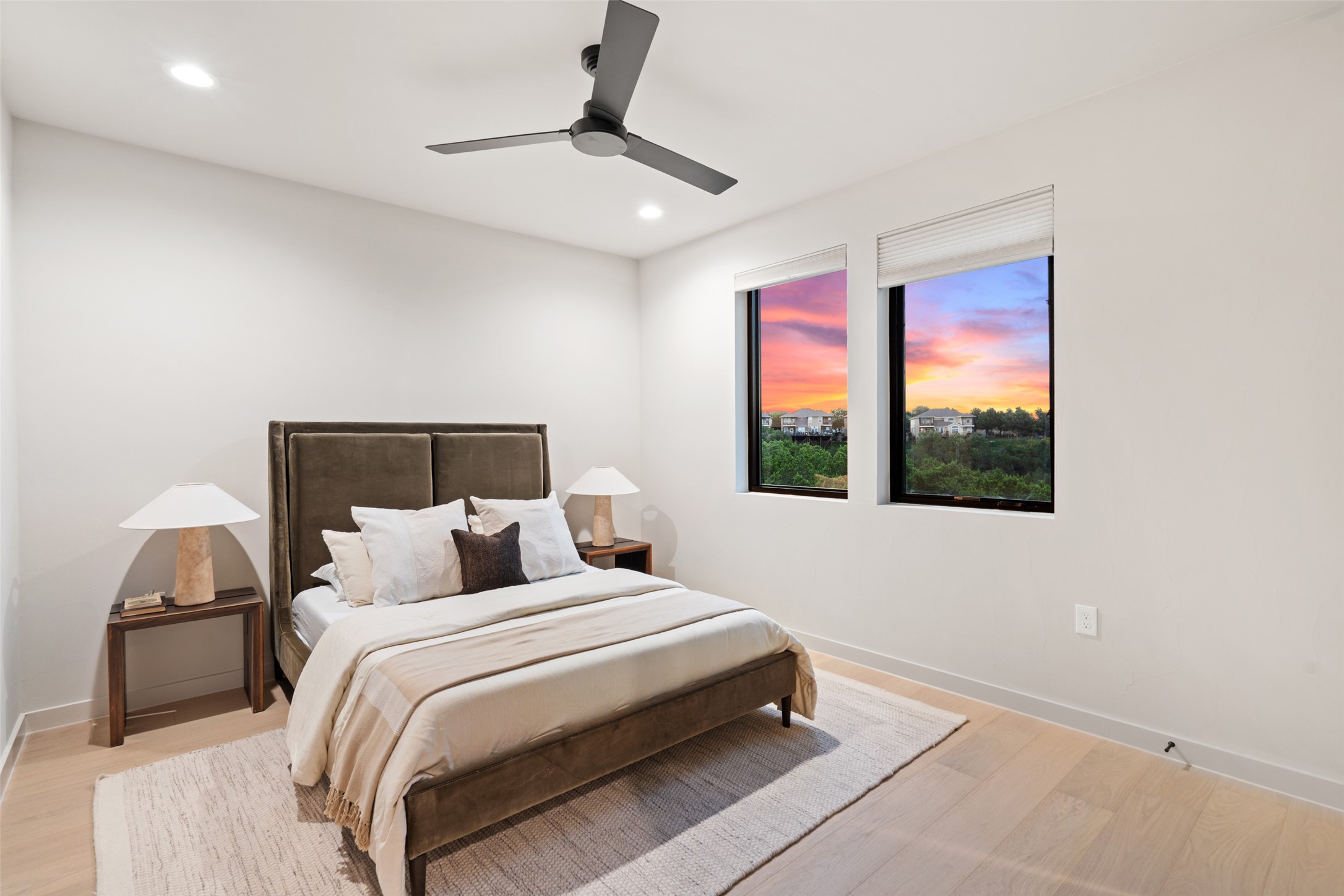 9803 Ribelin Ranch Court, Unit 6 Austin, TX 78750 - Photo 22 of 31 Recessed lighting and a sleek ceiling fan illuminate this inviting bedroom, offering picturesque views of a colorful sunset.