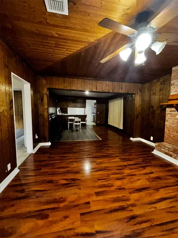 a view of an empty room with wooden floor fireplace and a window