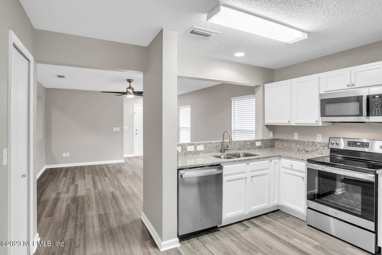 a kitchen with a sink cabinets stainless steel appliances and a window