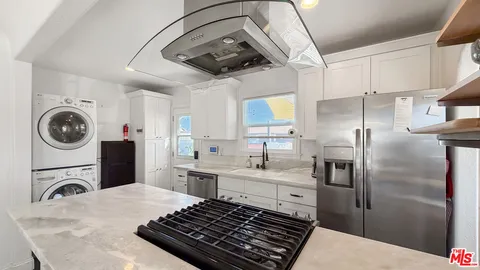 a kitchen with stainless steel appliances granite countertop a sink a stove a refrigerator and cabinets