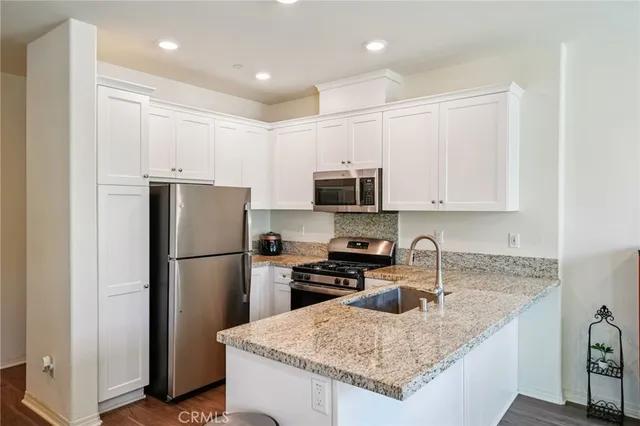 a kitchen with granite countertop a refrigerator a sink a stove a microwave and island
