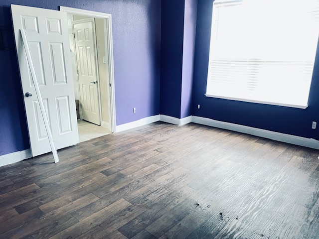 107 East Wheeler Street Manor, TX 78653 - Photo 5 of 7 an empty room with wooden floor and windows