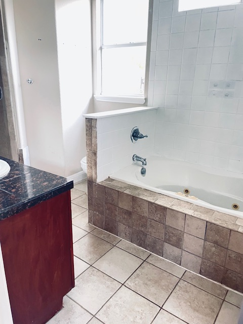 107 East Wheeler Street Manor, TX 78653 - Photo 6 of 7 a spacious bathroom with a granite countertop sink and a mirror